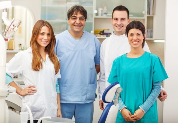 Group of dentists standing in their office and looking at camera.